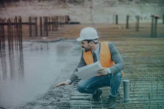 Inspecting poured concrete slab on building site
