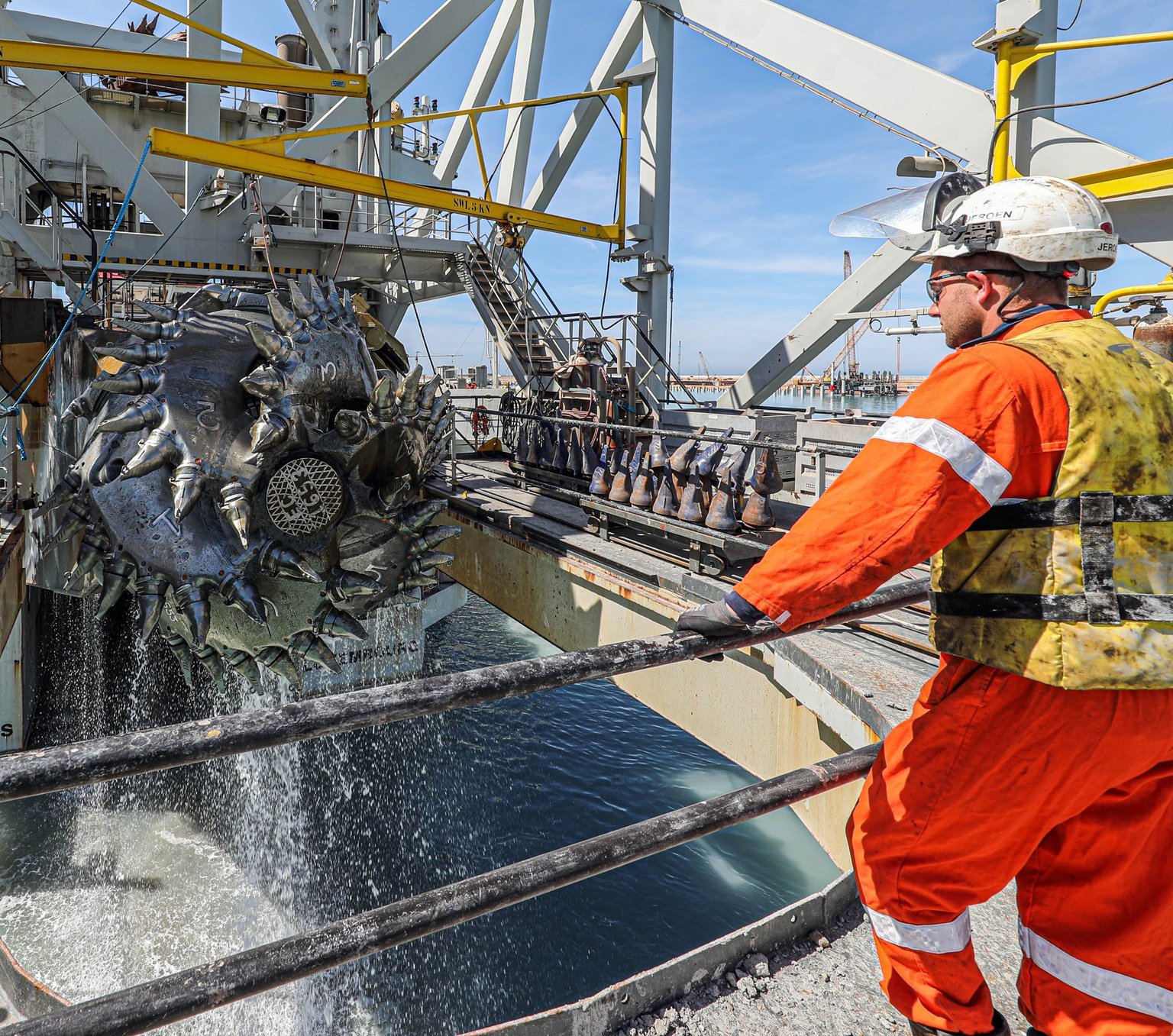Worker watches cutterhead lifted from sea on Jan De Nul dredging vessel
