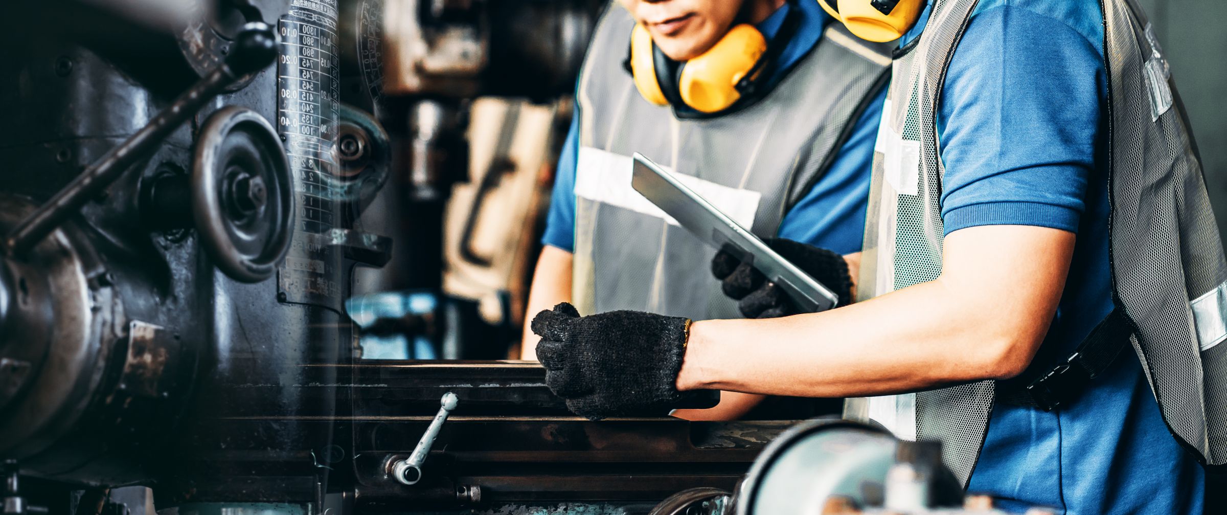 Two men in a factory working together on a machine, showcasing their skills and dedication in a manufacturing setting.